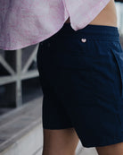 Close up of a luxury quality linen shirt tail in pink Pangolin pattern worn with sustainably made navy blue swim shorts at Basil's Bar on Mustique Island