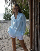 Woman wearing a light blue linen shirt in Sealeaf pattern on vacation, Dolly beach Mustique