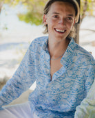 Man wearing a Pink House linen shirt in blue Pangolin pattern on a beach vacation at Brittania Bay, Mustique Island