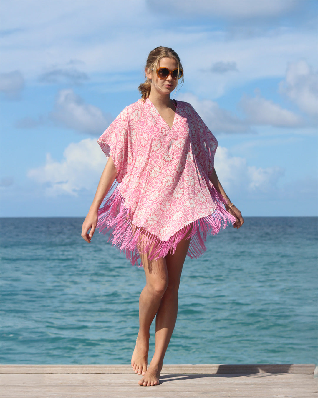 Twirling the Lotty B silk poncho in coral pink Sand Dollar pattern on the Cotton House beach bar pier, Mustique