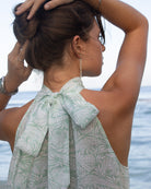 Close up showing elegant bow tied at the back of the neck on the linen Trinny dress in green Pangolin design. Holiday styling on Mustique Island