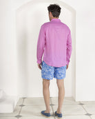 Pink House model Joss wears mens mid length recycled, swim shorts in signature blue Toile de Jouy in classic style with fuchsia pink pure linen shirt