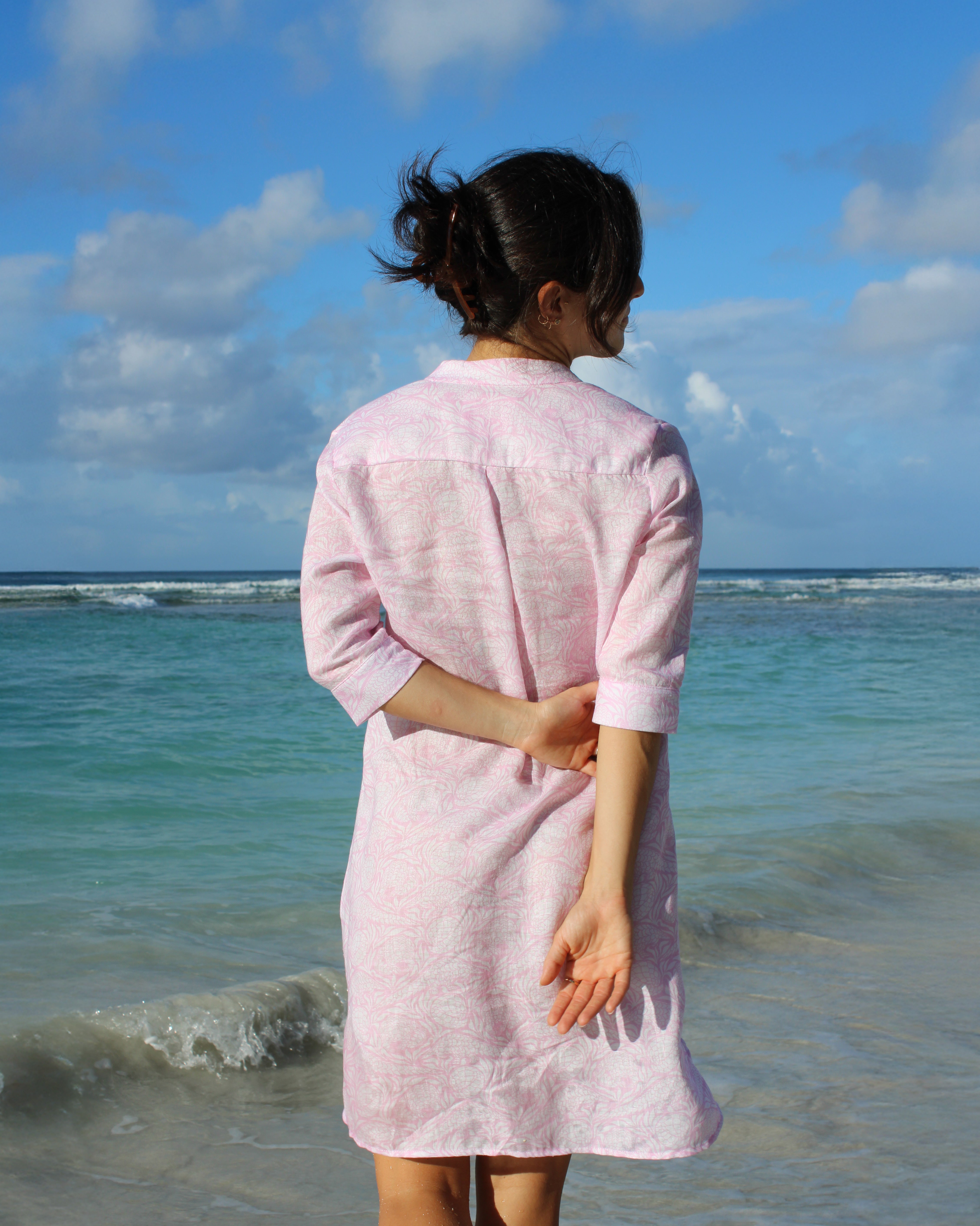 Woman in a pink Pangolin linen Decima dress standing in tropical waters on vacation, Mustique Island