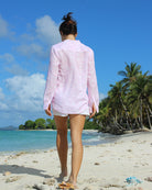 Woman walking along the beach on vacation in a linen Kim shirt in pink Pangolin print worn with classic white linen shorts on Lagoon Bay, Mustique island