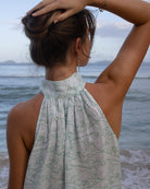 Model Lottie styling a reversible linen maxi dress in green Pangolin design on holiday at Dolly beach, Mustique Island