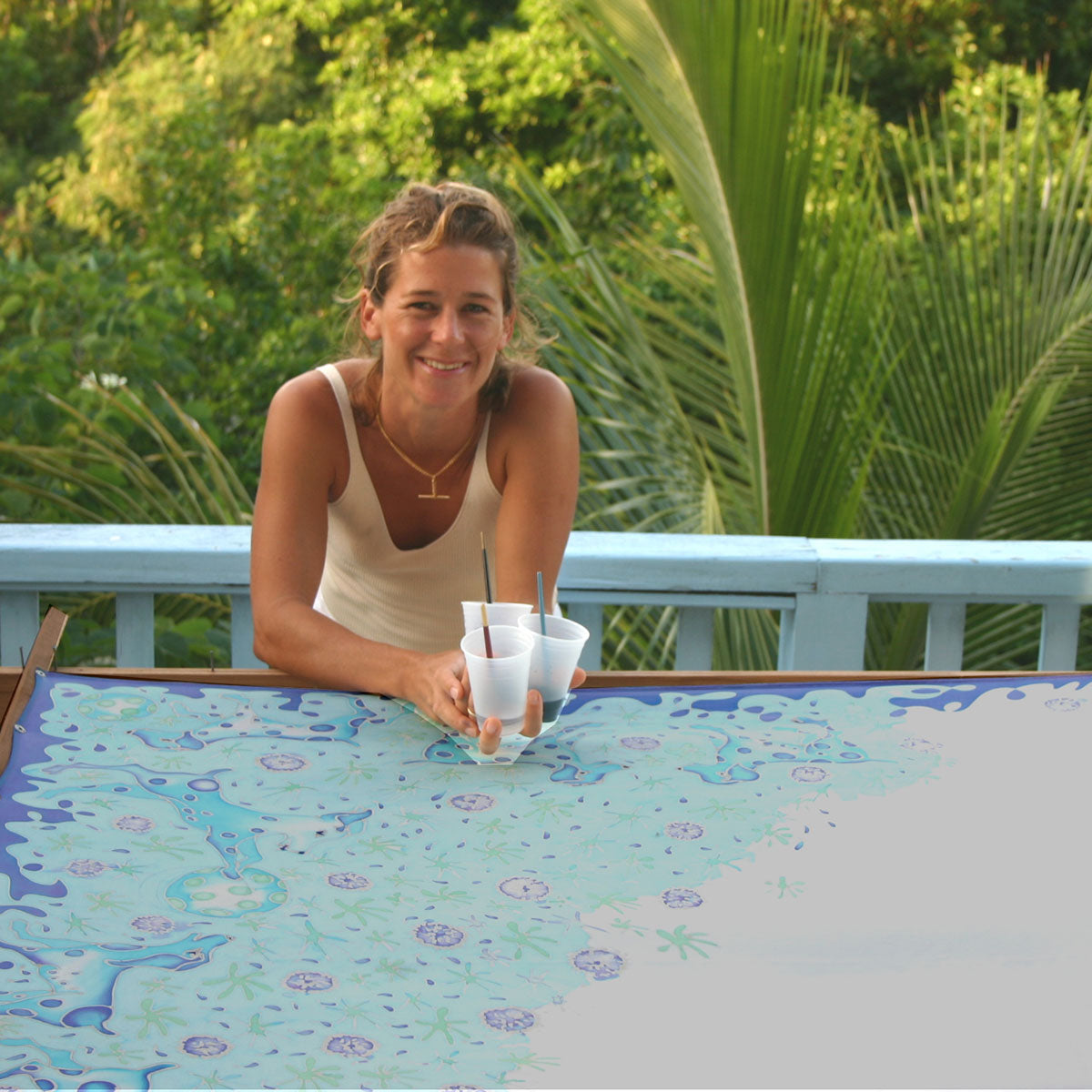 In the early days British designer Lotty B hand painted every sarong. Picture shows Lotty leaning over a half painted silk sarong with cups of silk paints in her hand.