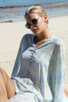 Lotty B Short Kaftan in Silk Crepe-de-Chine: PINEAPPLE - OLIVE sitting on the beach Mustique