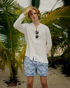 Tropical island holiday essentials for mens recycled, swim shorts in signature blue Toile de Jouy worn with classic white collarless linen shirt