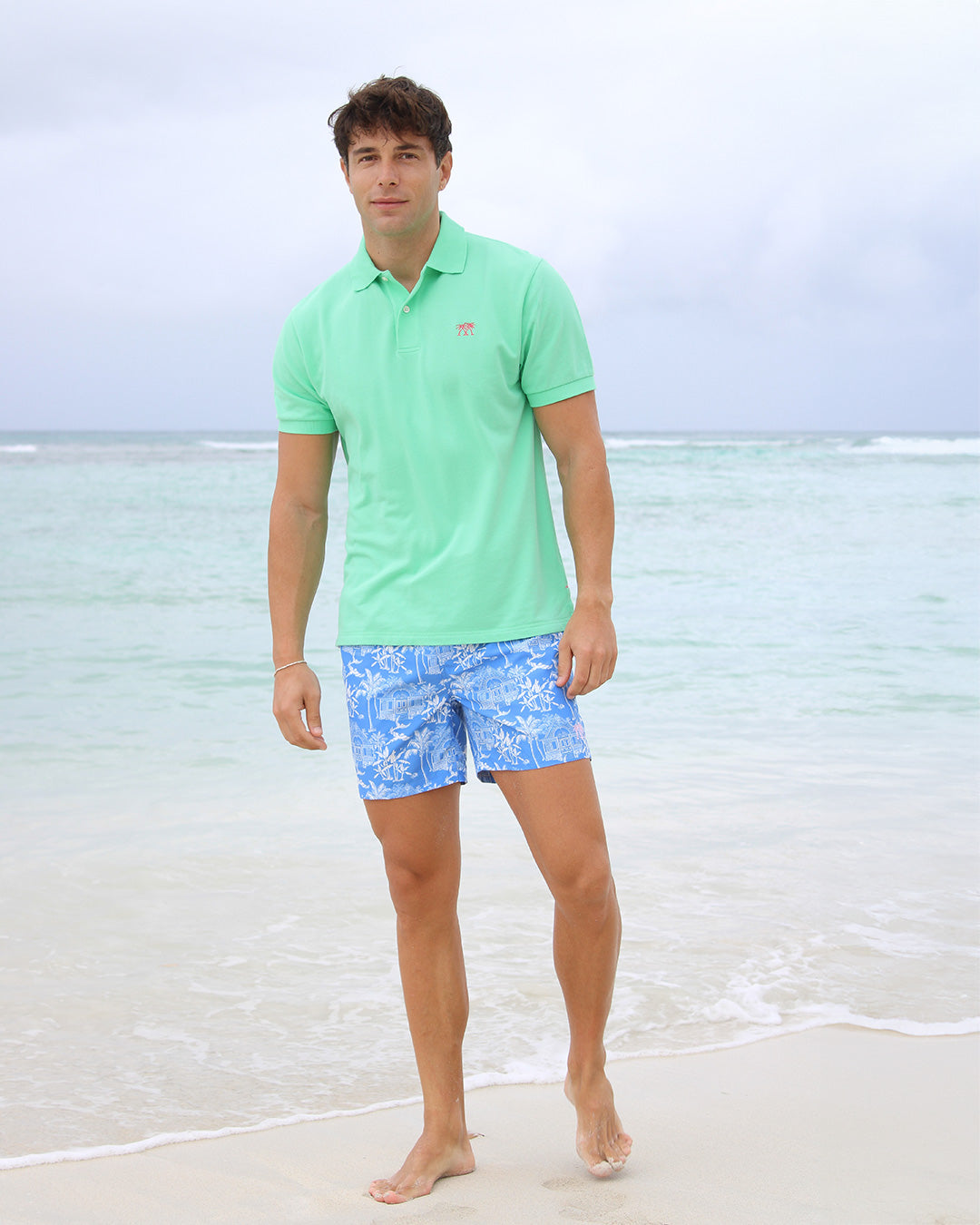 Pink House beach classics mens recycled, swim shorts in signature blue Toile de Jouy worn with bright green cotton polo shirt