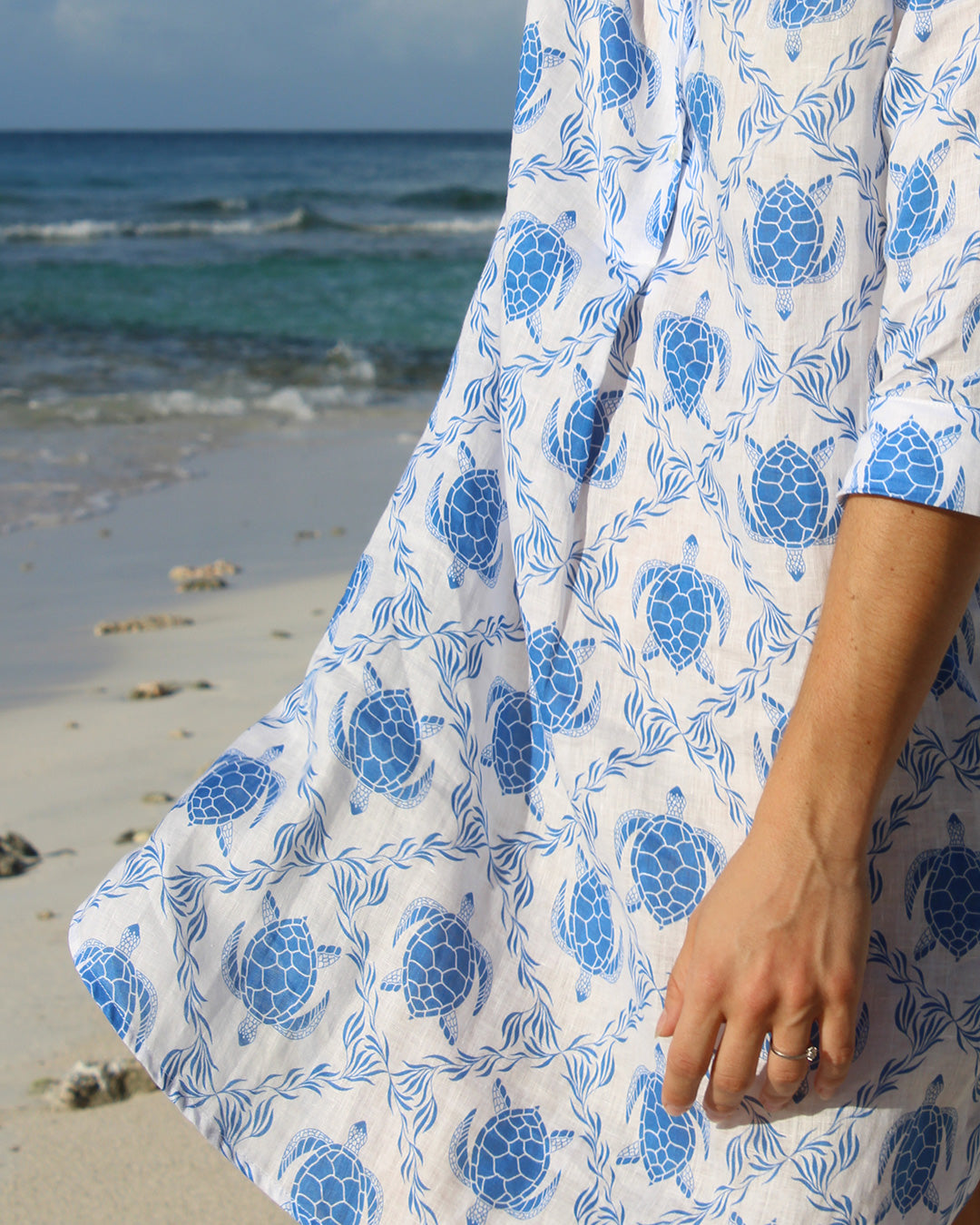 Close up detail of quality linen Decima dress in blue Turtle print on vacation, Mustique Island