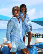 Father and son wearing matching linen shirts and sustainable swim shorts in blue Pangolin pattern on holiday at the Cotton House pier on Mustique Island