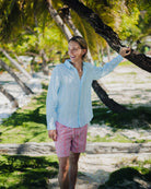 Man leaning on a tree on holiday in a quality linen shirt in blue Sealeaf pattern at Brittania Bay, Mustique Island