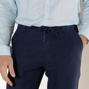 Men's comfy vacation linen pants in eclipse navy blue worn with pale blue linen shirt