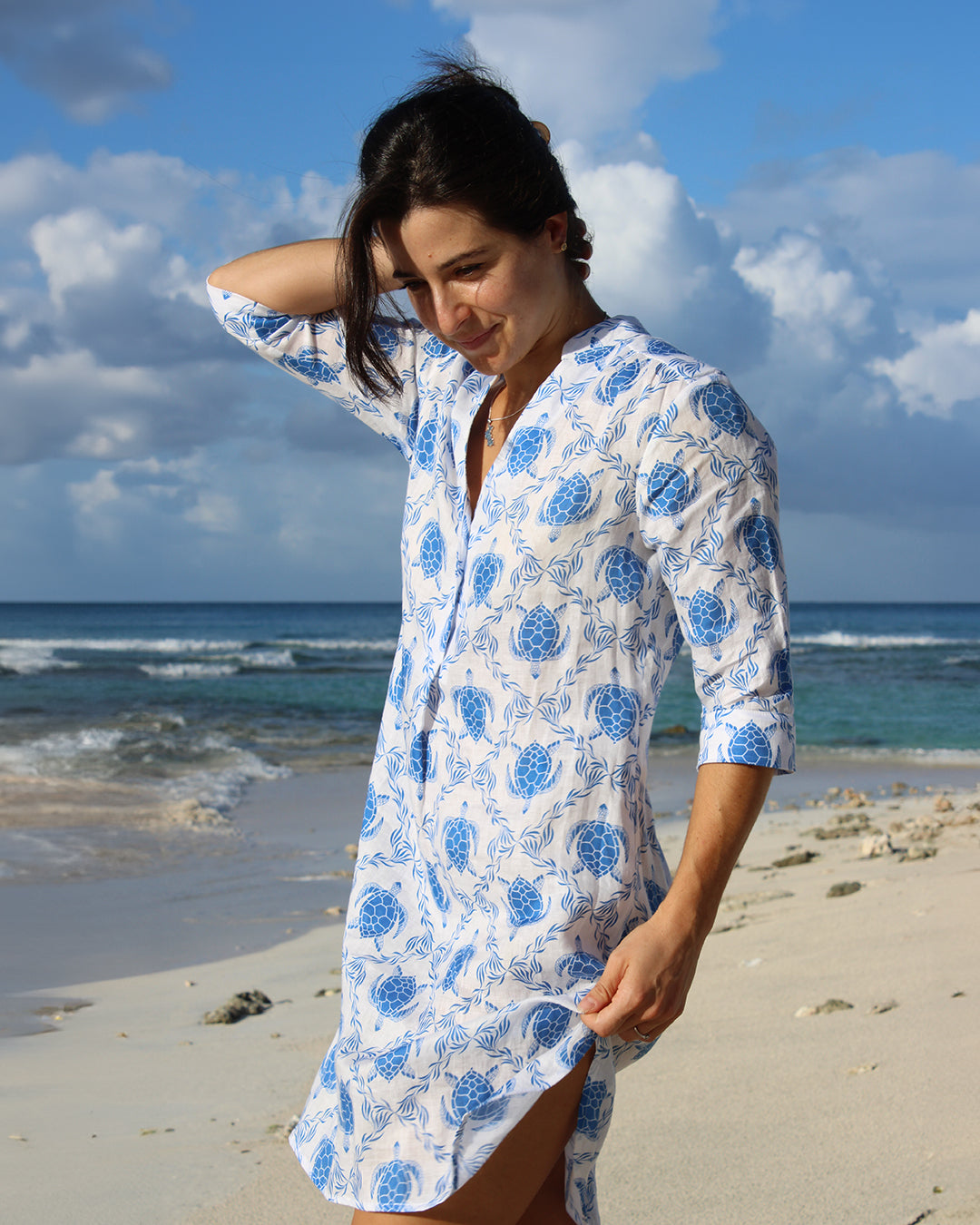 Woman styling chic linen beach dress in blue Turtle print on Lagoon bay, Mustique Island