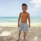 Kids tropical holiday styles in sustainable turquoise blue swim shorts with red and blue Riva boat print