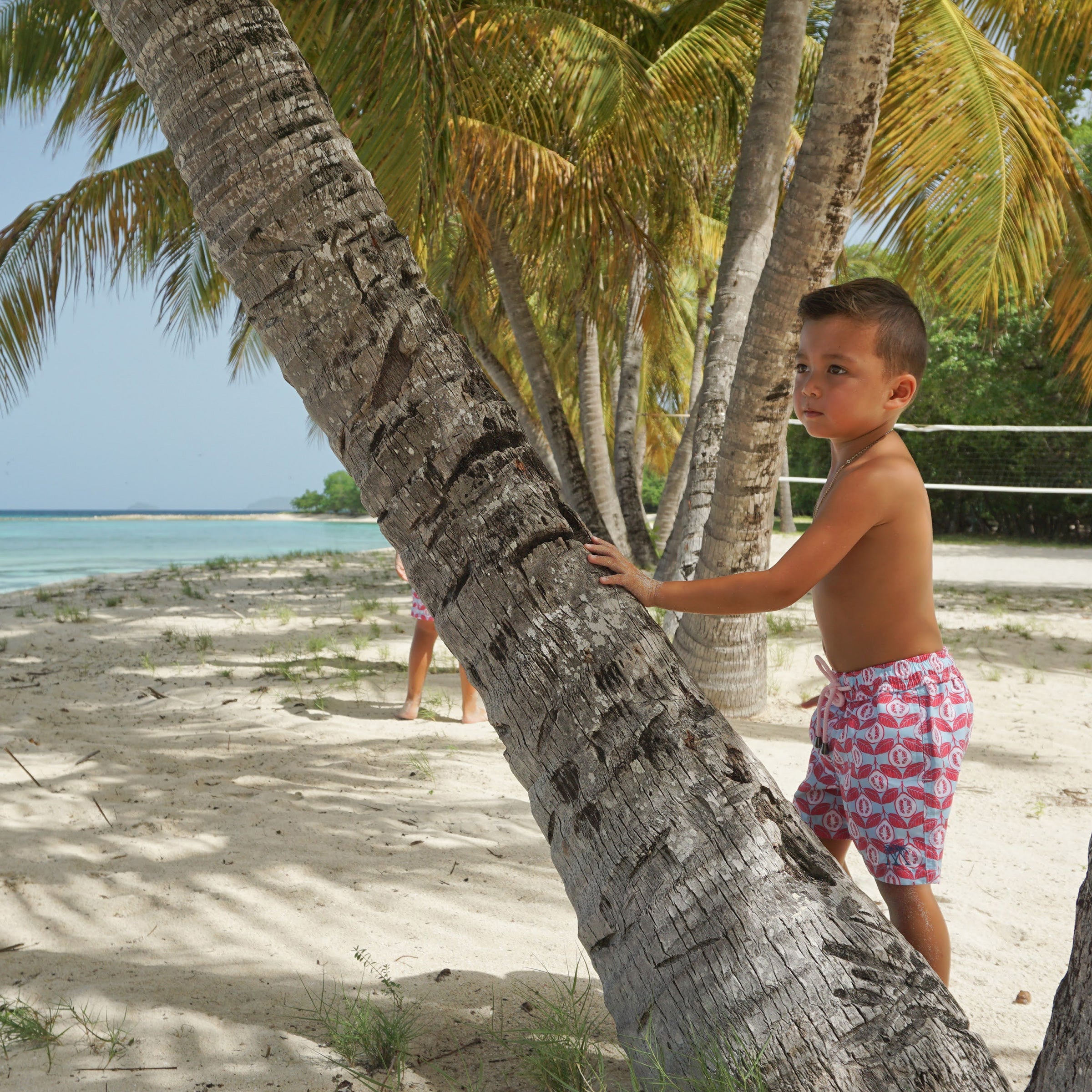 Boys summer swim shorts in Guava red print by designer Lotty B Mustique travel shop