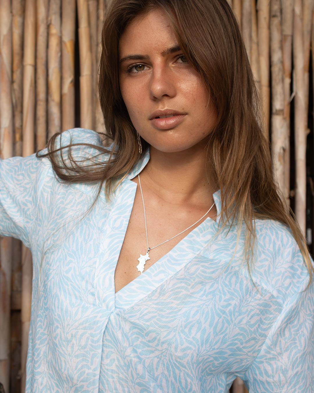 Close up showing quality linen shirt with Mandarin collar and v neck in light blue Sealeaf pattern with a diamante and silver island pendant necklace